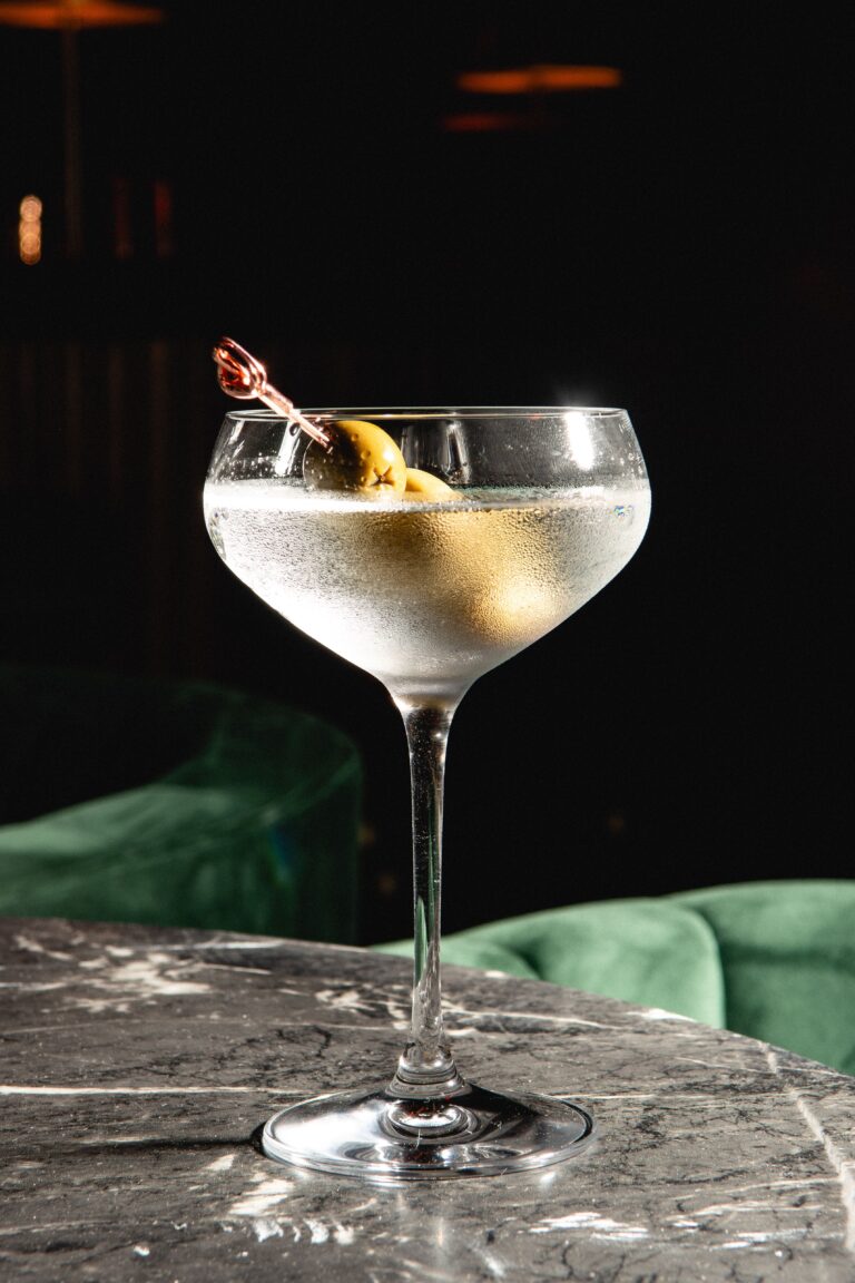 Crystal cocktail glass graces the marble-finished table, lending an elegant touch to the setting.