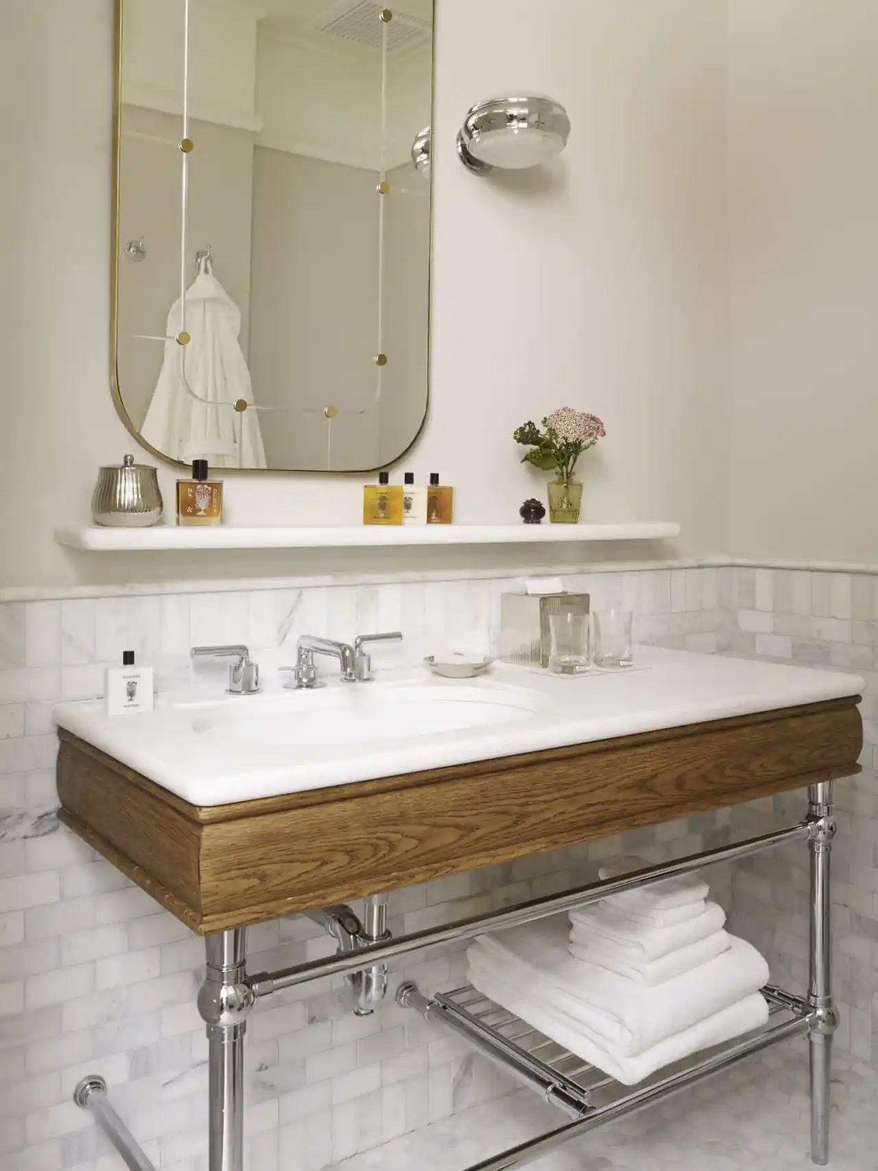Large size mirror hanging just above the wash basin and some towels are kept just below the wash basin