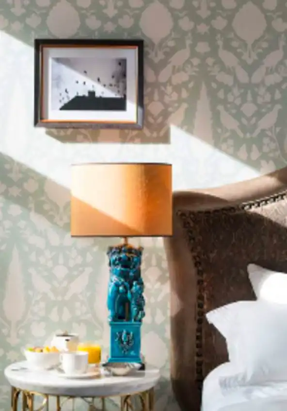 Blur image of a handmade table lamp with a breakfast tray lying on the side table of the bed