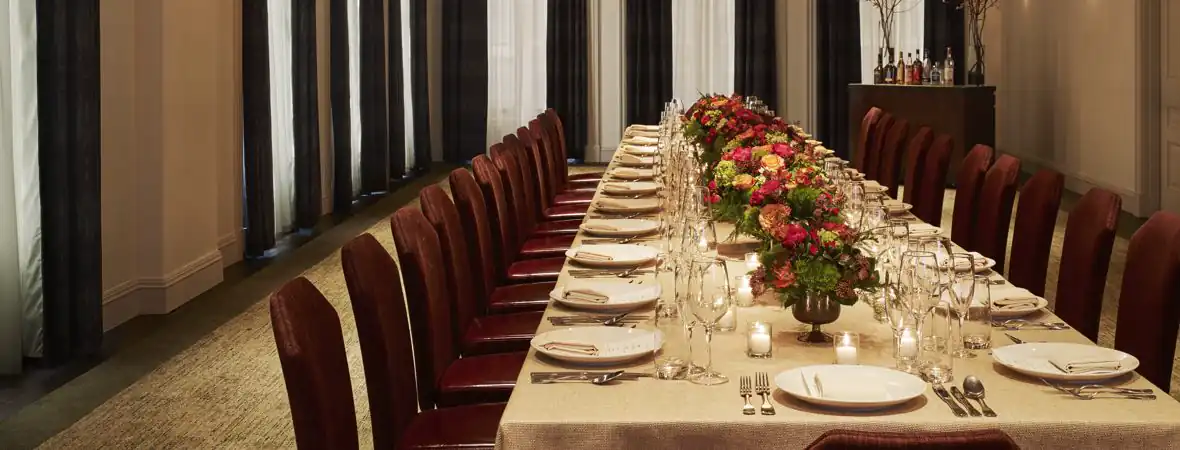 Long dining table decorated with flower vase and some cutlery