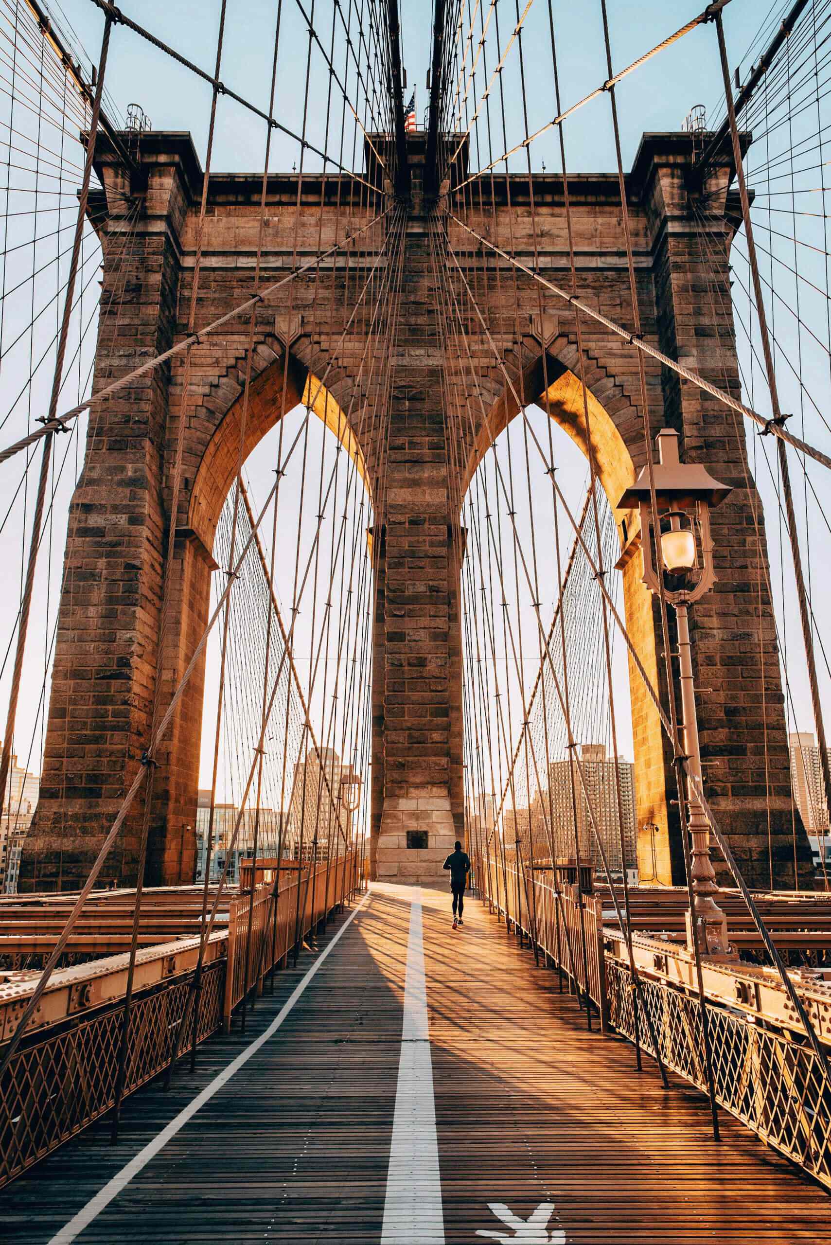 A man is jogging on the famous Brooklyn Bridge