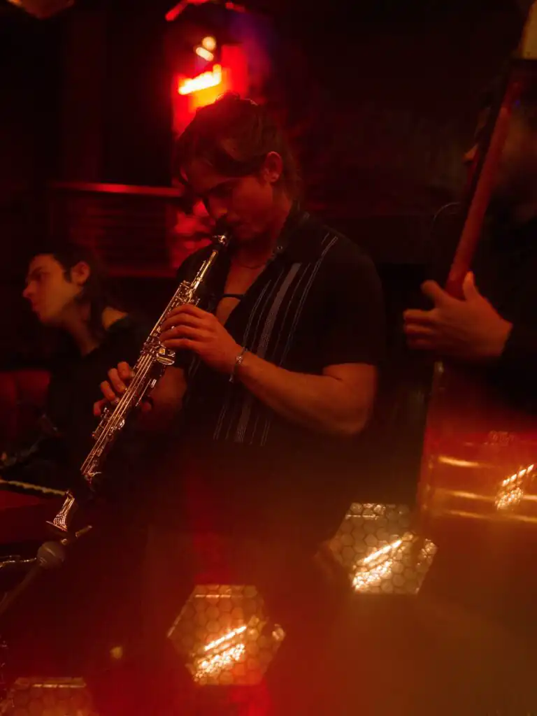 A guy playing clarinet under red lighting, creating a captivating musical ambiance.
