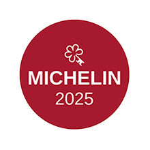 Red circular badge with white flower and key icon above “MICHELIN 2025” in bold white letters.